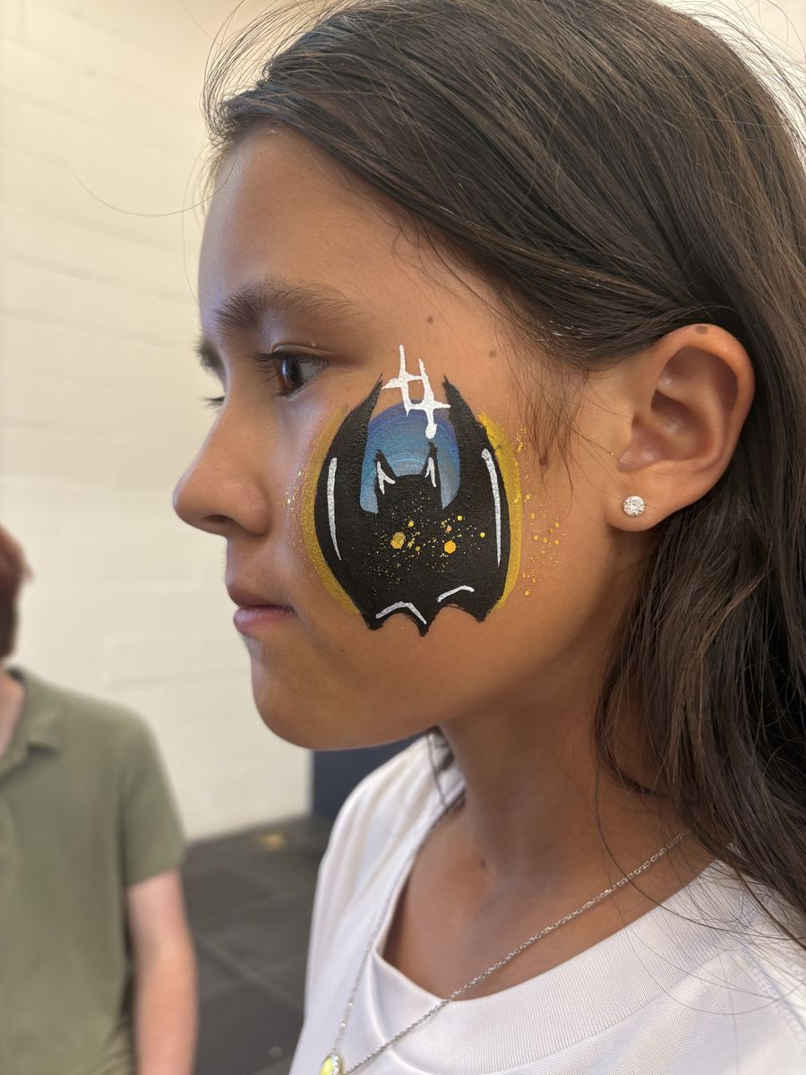 Black bat emblem cheek design on a blue and gold background with white detail lines