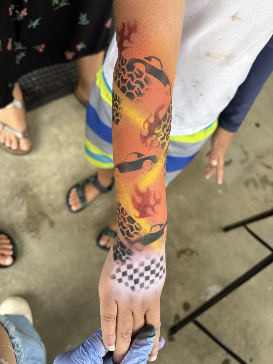Airbrushed race car arm sleeve with flames, tire tracks and a checkered finish flag on the wrist