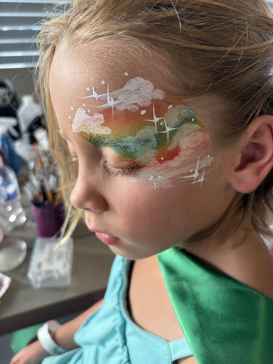 Soft rainbow and white cloud eye design with painted sparkles across the brow and temple