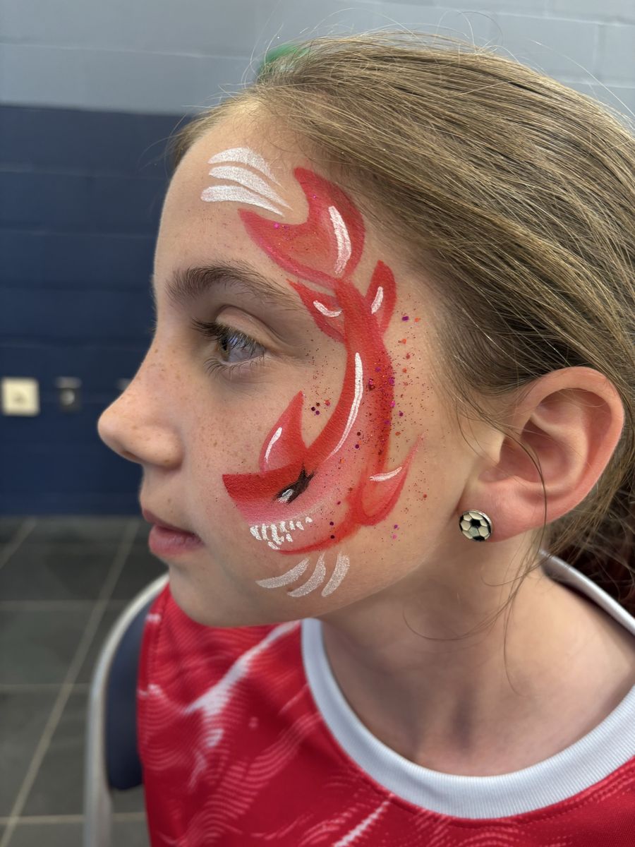 Bold red shark cheek design with white highlights and glitter, painted from temple to jaw